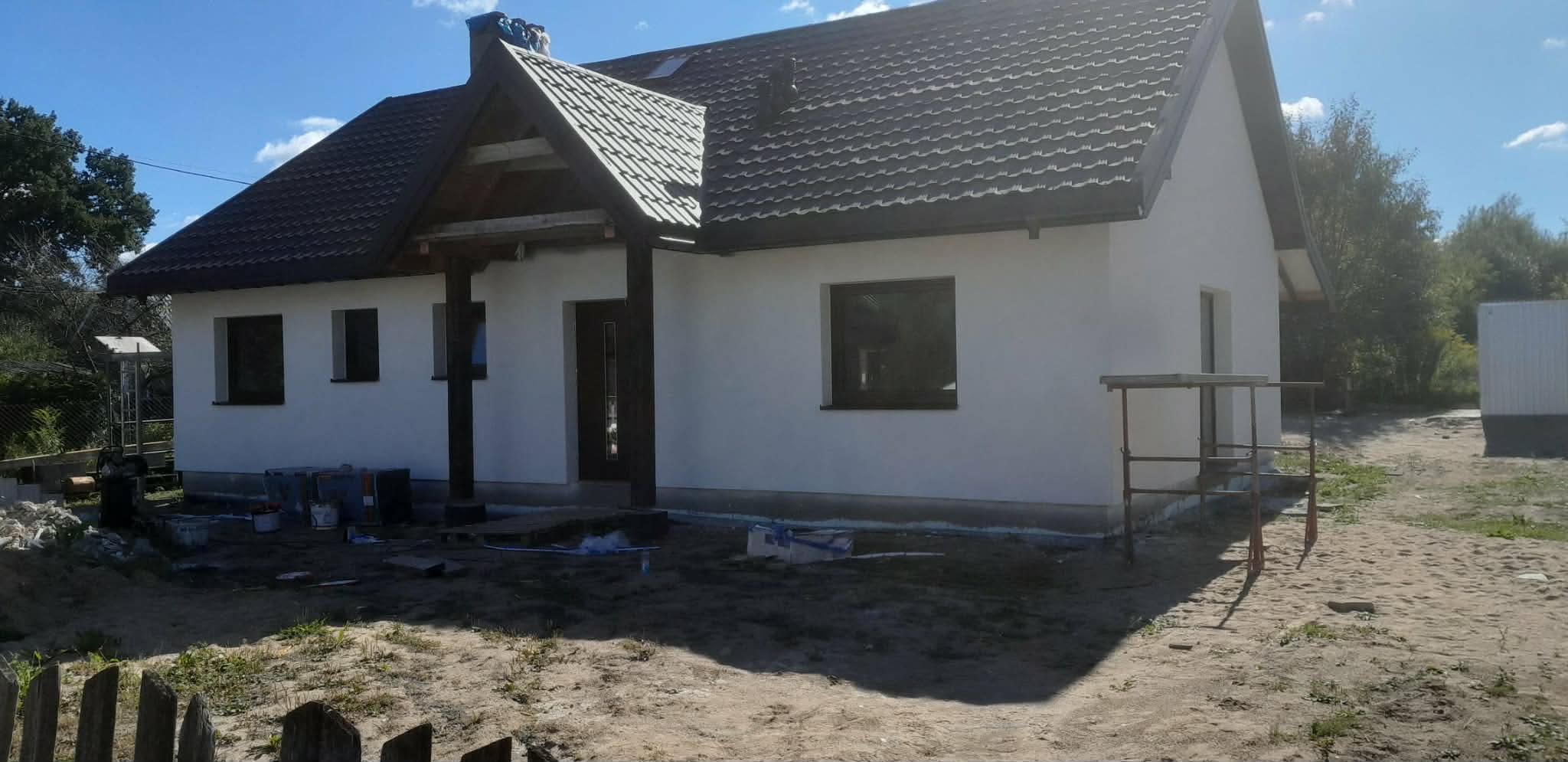 Otynkowana elewacja domu z zadaszonym wejściem